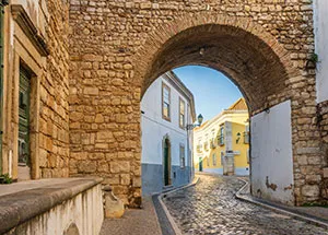 Arco de pedra sobre uma rua calcetada de um centro histórico